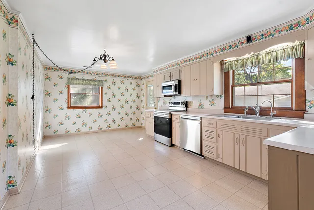 a large white kitchen with a stove a sink and dishwasher with white cabinets