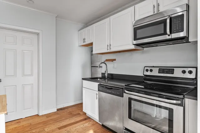 a kitchen with white cabinets stainless steel appliances and wooden floor
