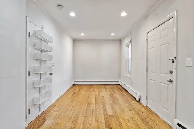 a view of a hallway with wooden floor and a bathroom