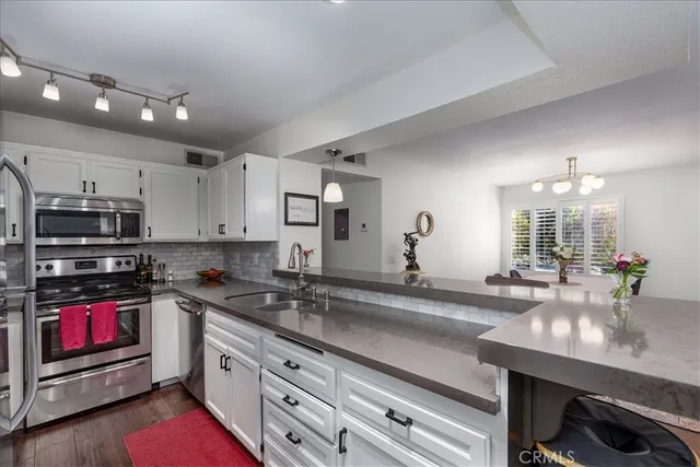 a kitchen with stainless steel appliances granite countertop a sink dishwasher stove and cabinets with wooden floor