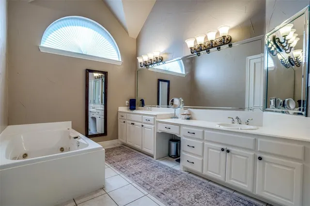 a bathroom with a tub a double vanity sink and a mirror
