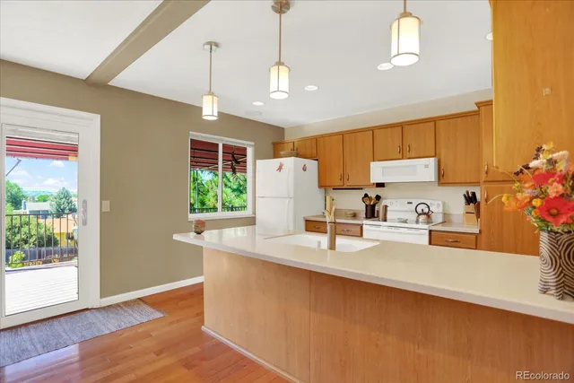 a kitchen with stainless steel appliances granite countertop a refrigerator a sink dishwasher a stove and white countertops with wooden floor