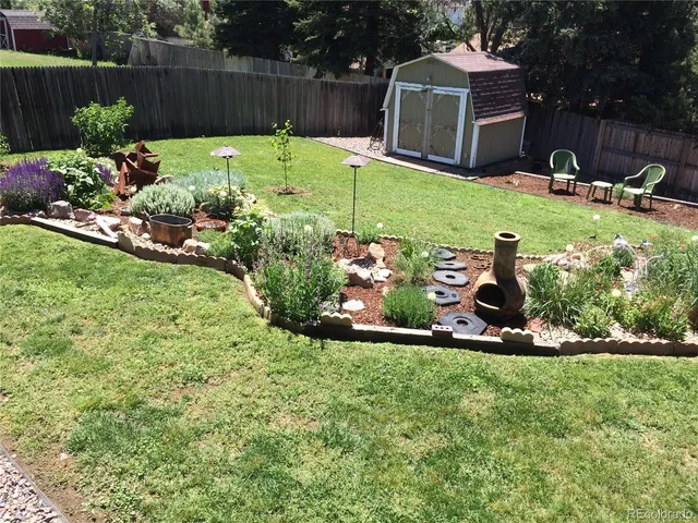 a view of a backyard with plants and a fence