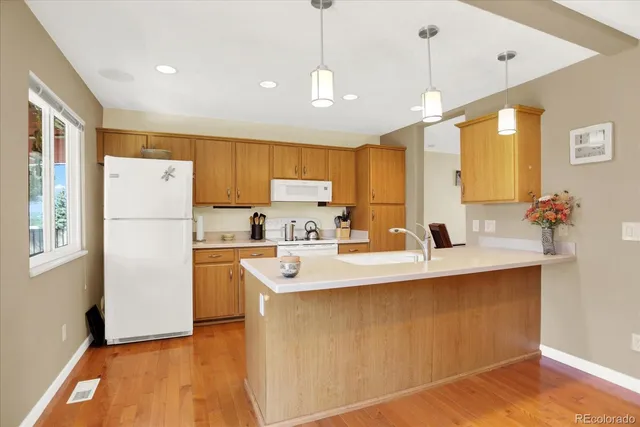 a kitchen with stainless steel appliances granite countertop a refrigerator a sink dishwasher a oven with white cabinets and wooden floor