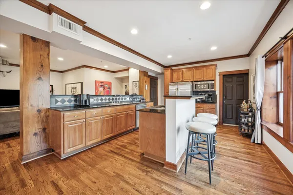 a kitchen with stainless steel appliances granite countertop a refrigerator a stove top oven and a dining table with wooden floor