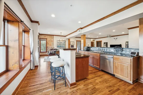 a kitchen with stainless steel appliances granite countertop a refrigerator a sink dishwasher a stove and white cabinets with wooden floor