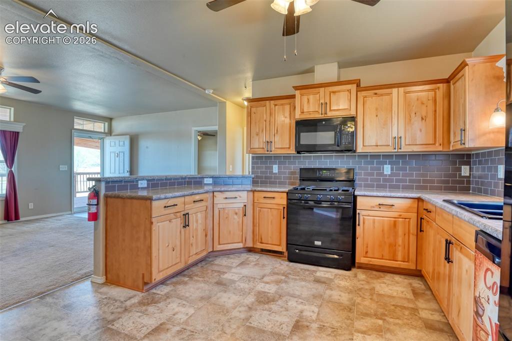 22558 Enoch Road Calhan, CO 80808 - Photo 9 of 50 a kitchen with granite countertop a stove top oven microwave and cabinets