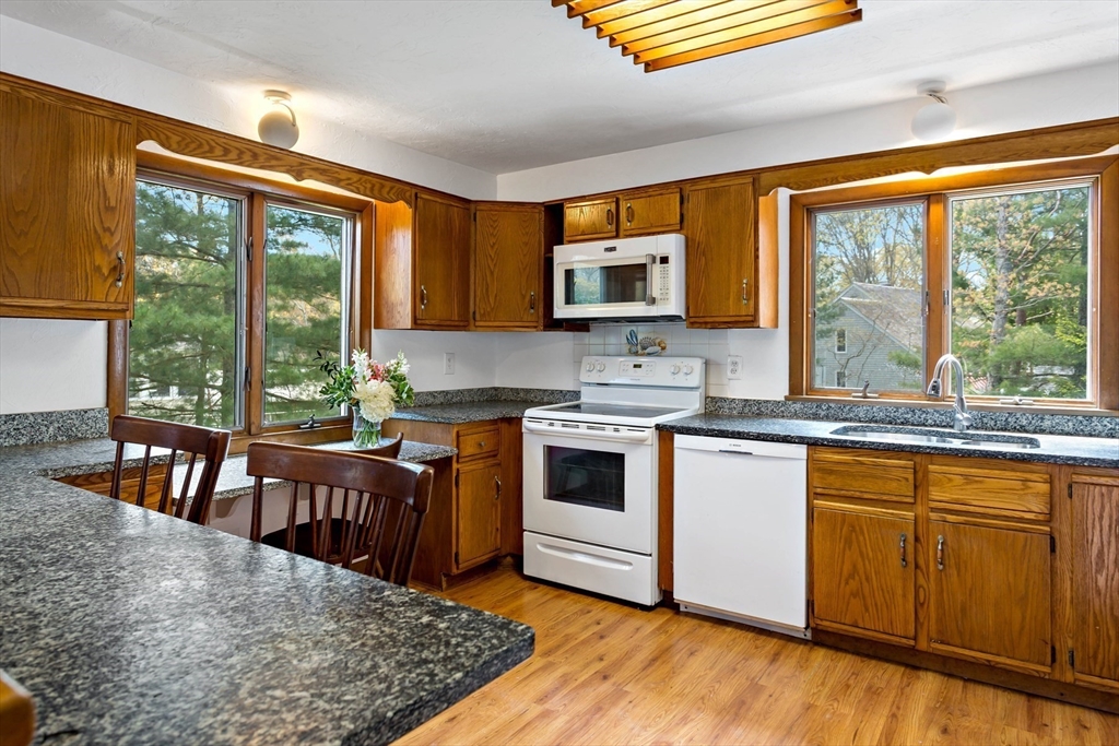 11 Tupelo Road Marstons Mills, MA 02648 - Photo 10 of 37 a kitchen with stainless steel appliances granite countertop a stove a sink dishwasher a microwave oven with a dining table and chairs with wooden floor