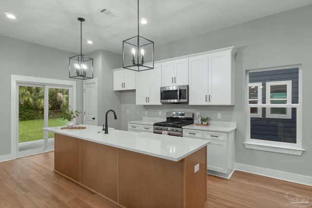 a kitchen with stainless steel appliances granite countertop a sink a stove a microwave cabinets and a wooden floor