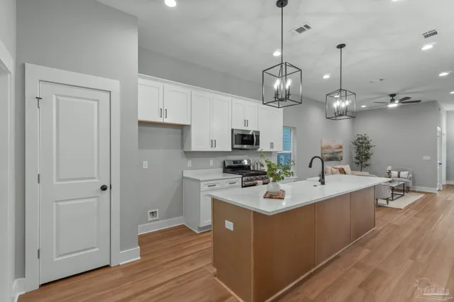 a kitchen with a sink stainless steel appliances a counter top space cabinets and wooden floor