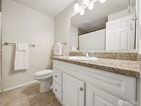a bathroom with a granite countertop sink a toilet and a mirror