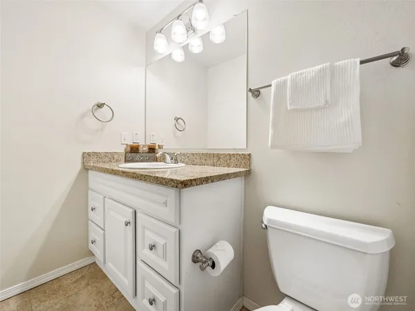 a bathroom with a granite countertop sink mirror vanity and toilet