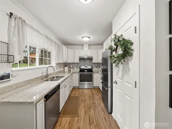 a kitchen with a sink a counter top space stainless steel appliances and a window