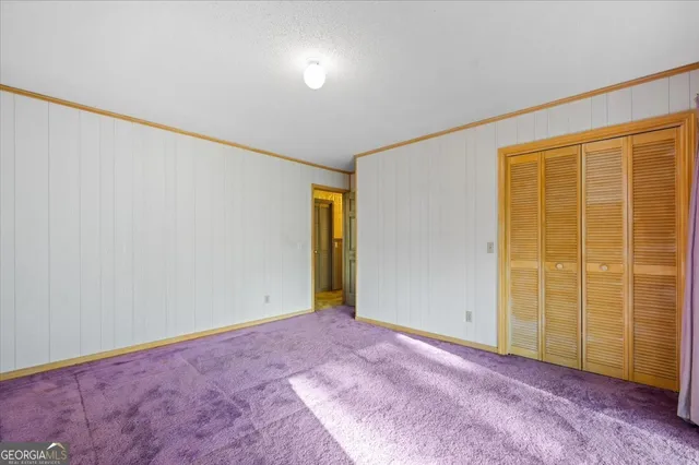 a view of a hallway with wooden floor and a bathroom