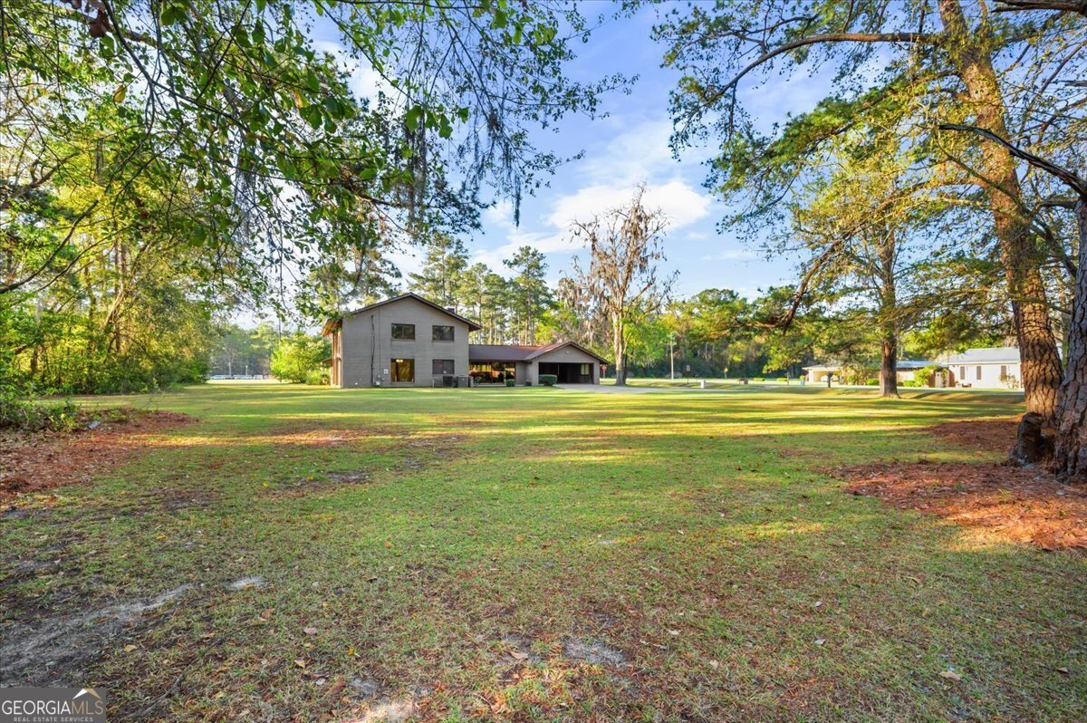 2066 Cherokee Street Waycross, GA 31503 - Photo 48 of 56 a view of a house with a big yard and large trees