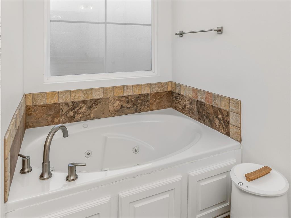 690 Lessie Drive Stonewall, LA 71078 - Photo 19 of 29 Built-in corner soaking tub featuring a tiled surround with stone-finish accents and brushed nickel fixtures