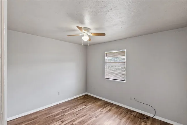 an empty room with a window and ceiling fan