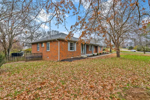 a backyard of a house with large trees and outdoor seating
