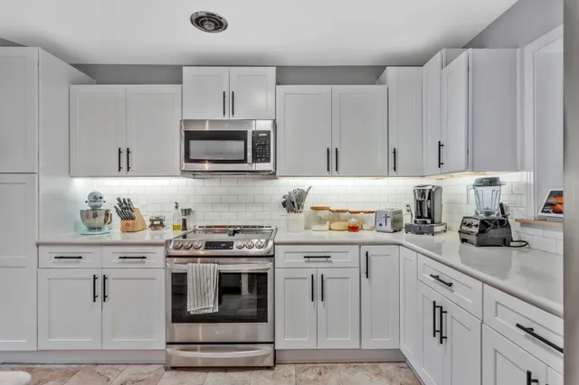 a kitchen with granite countertop white cabinets and white appliances