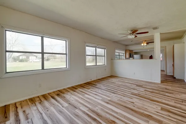 a view of an empty room with a window and wooden floor