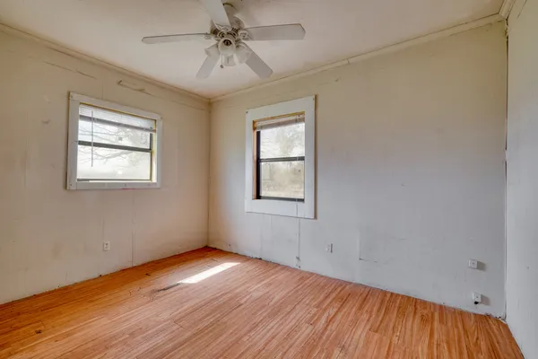 a view of empty room with wooden floor and fan