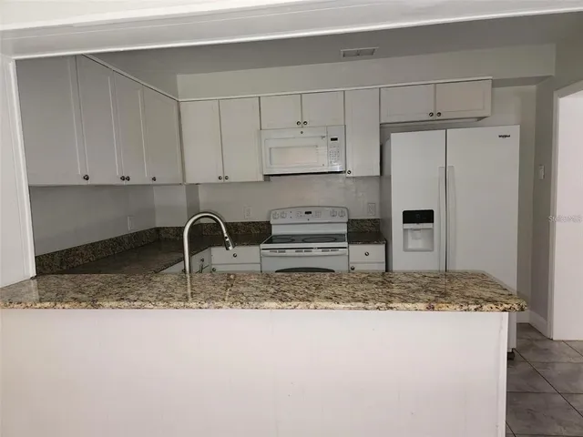 a kitchen with granite countertop a stove a refrigerator and a sink