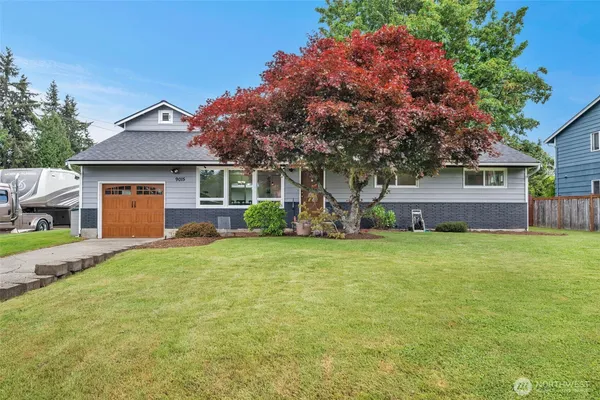 a front view of house with yard and trees in the background
