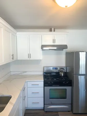 a kitchen with granite countertop white cabinets and stainless steel appliances