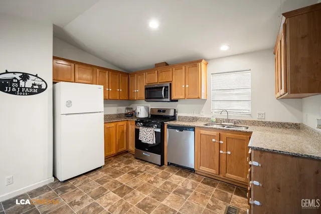 a kitchen with stainless steel appliances granite countertop a refrigerator sink and stove