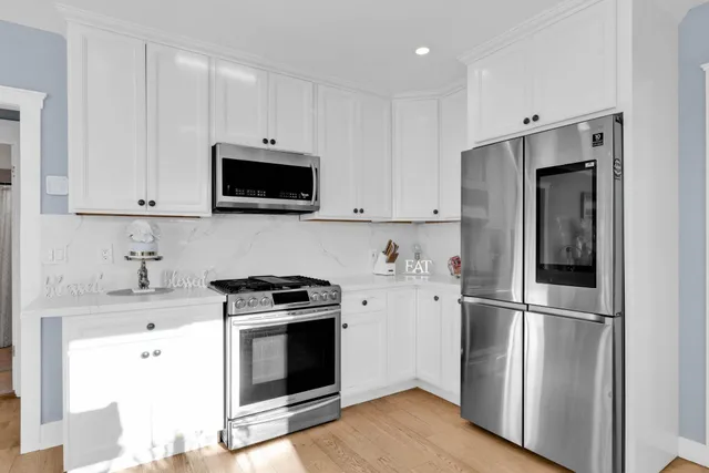a kitchen with stainless steel appliances white cabinets and a stove a refrigerator with wooden floor