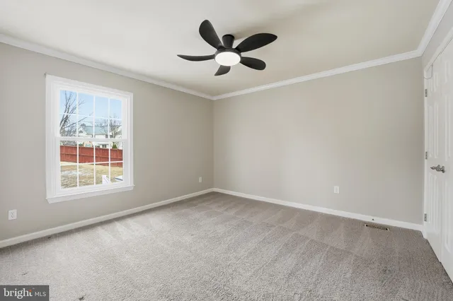 an empty room with wooden floor and ceiling fan