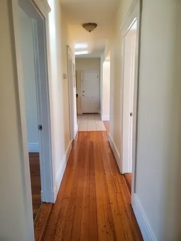 a view of a hallway with wooden floor and a bathroom