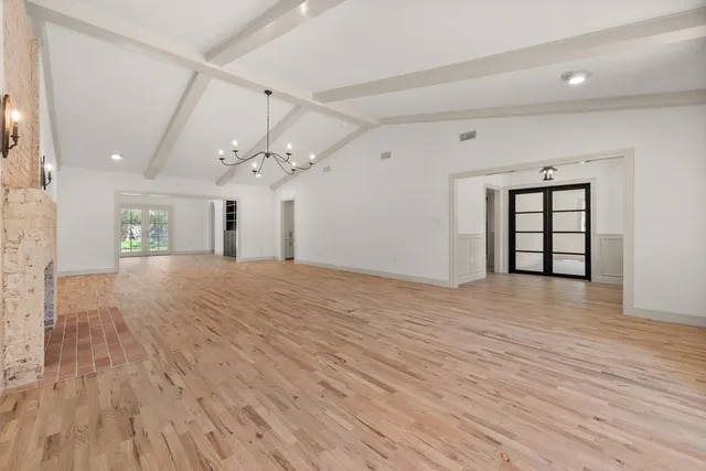 a view of a livingroom with a chandelier fan and wooden floor