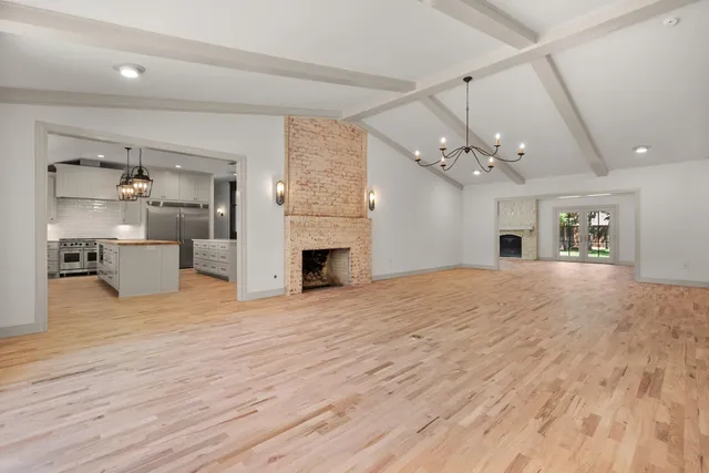 a view of a livingroom with a fireplace a chandelier and wooden floor