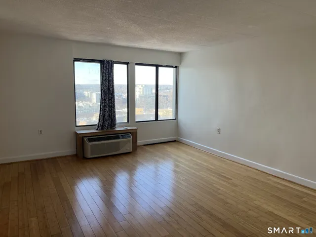 a view of an empty room with wooden floor and a window