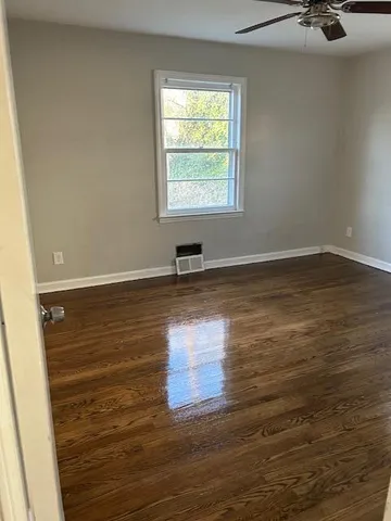 a view of empty room with wooden floor and window