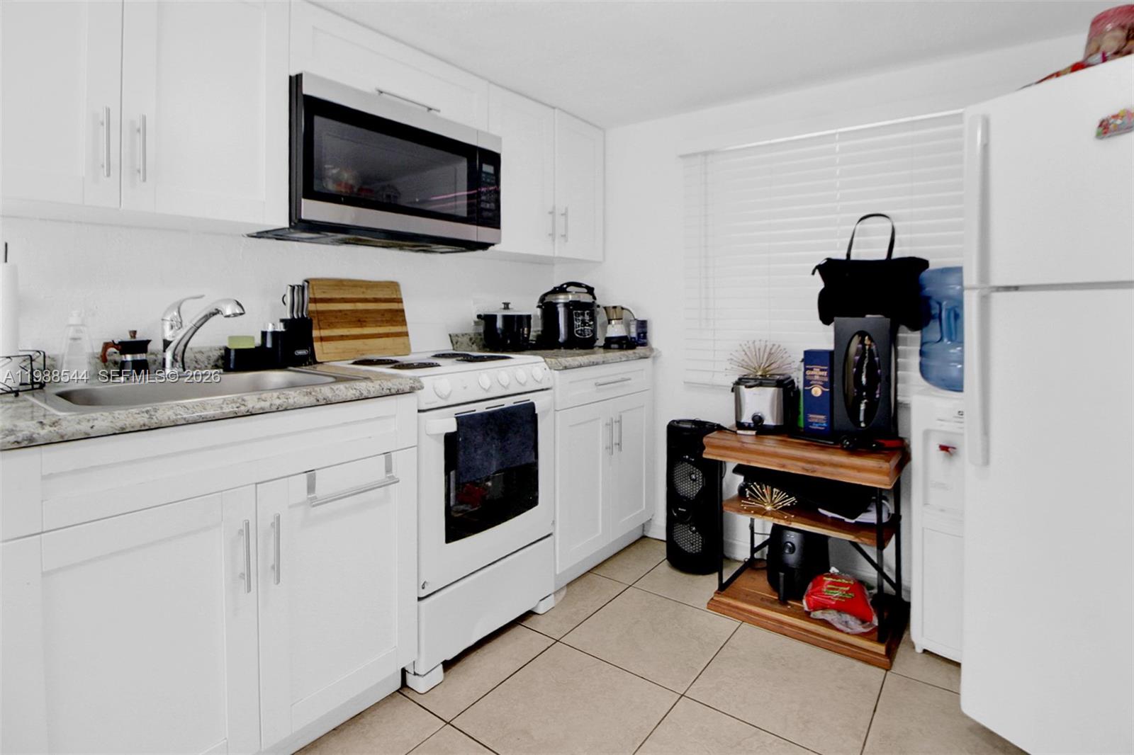 2900 Northwest 95th Street Miami, FL 33147 - Photo 7 of 48 a kitchen with white cabinets a sink and a stove with wooden floor