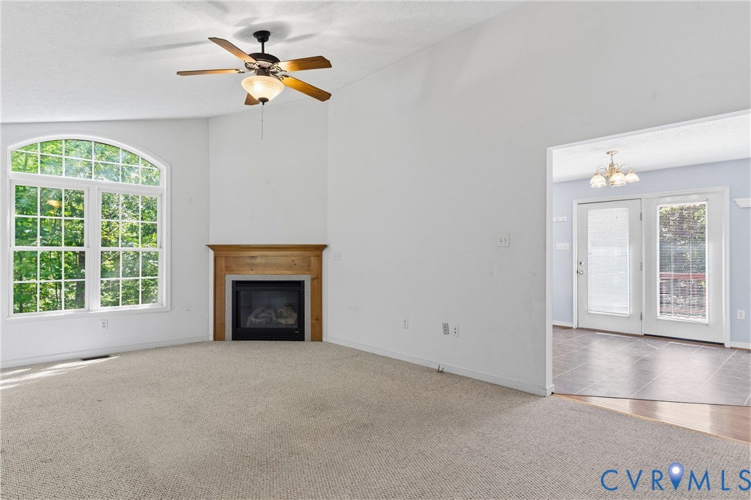 12654 Mt Olive Cohoke Road West Point, VA 23181 - Photo 7 of 31 an empty room with windows fireplace and a chandelier fan