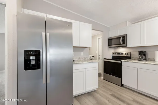 a kitchen with granite countertop white cabinets and a sink