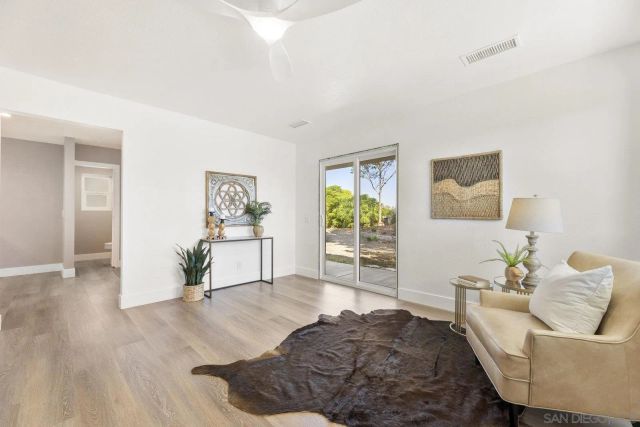 a view living room with wooden floor and clock