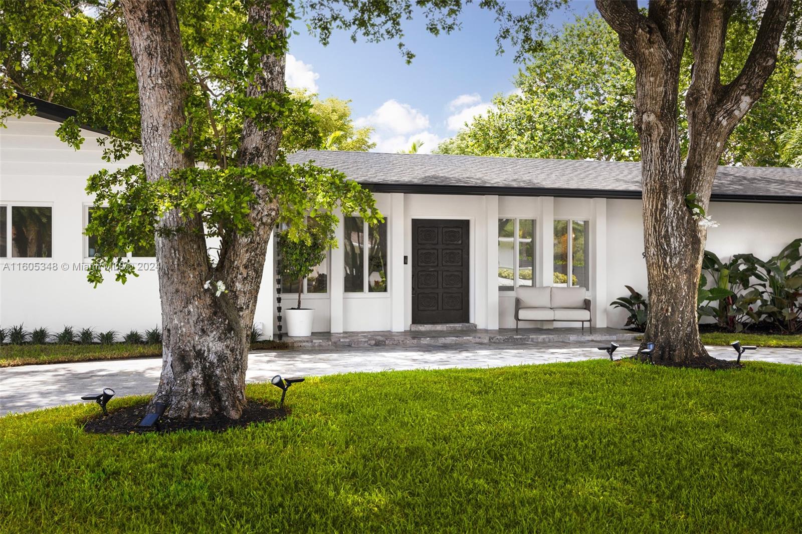 9800 Southwest 70th Avenue Pinecrest, FL 33156 - Photo 2 of 46 a front view of a house with a yard and an tree