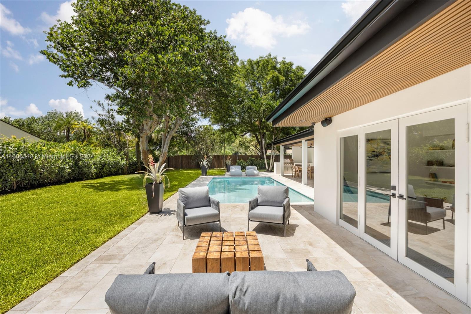 9800 Southwest 70th Avenue Pinecrest, FL 33156 - Photo 32 of 46 a view of a patio with couches potted plants and a big yard