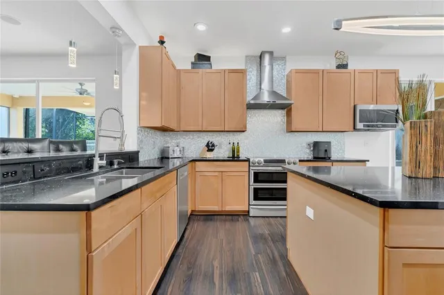 a kitchen with stainless steel appliances kitchen island granite countertop a stove a sink and a refrigerator