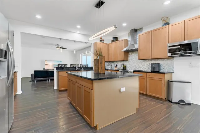 a large kitchen with stainless steel appliances refrigerator a stove a sink dishwasher with wooden floor and cabinets