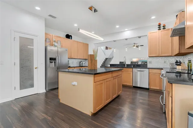 a kitchen with stainless steel appliances granite countertop a stove top oven a sink with a dining table and chairs