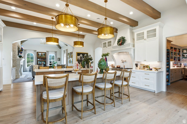 71 Farm Road Midway, UT 84049 - Photo 16 of 92 Spacious kitchen featuring an expansive central island with seating, exposed wood beam ceiling, contemporary pendant lighting, light wood-finish flooring, and white cabinetry