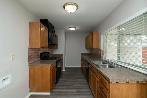 a kitchen with stainless steel appliances granite countertop a sink a stove and a wooden floors