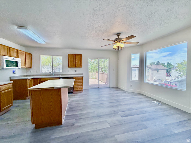 1705 80 East Tooele, UT 84074 - Photo 5 of 22 Open-concept living space featuring wood-finish flooring, a kitchen island, and a ceiling fan with integrated lighting