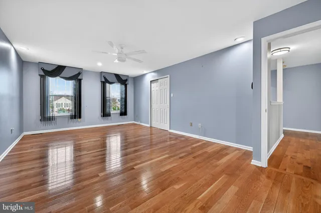 a view of an empty room with window and wooden floor