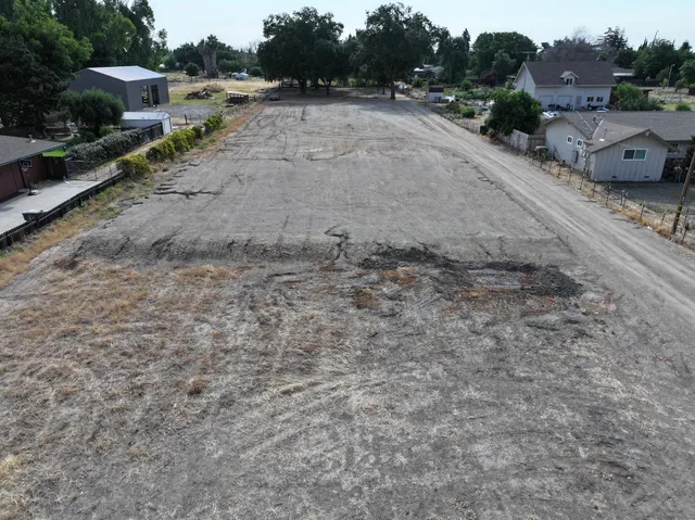 a view of a dry yard with wooden fence